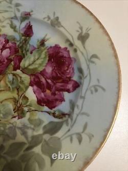Assiette ancienne de Limoges peinte à la main avec des roses roses et jaunes et des feuilles vertes.