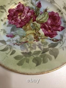 Assiette ancienne de Limoges peinte à la main avec des roses roses et jaunes et des feuilles vertes.